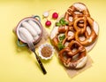 Pretzels and vegetables on yellow background, german traditional food, bavarian snack, european breakfast, oktoberfest