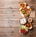 Pretzels, white bavarian sausages, beer and mustard and vegetables on wooden background, german traditional food, oktoberfest