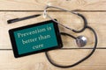 Prevention is better than cure - Workplace of a doctor. Tablet, medical stethoscope, black pen on wooden desk background