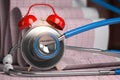 Prevention of heart disease, time to go to the cardiologist concept. Alarm clock and stethoscope with cardiogram