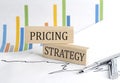 PRICING STRATEGY text on a wooden block on chart background , business concept