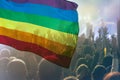 Colorful LGBT flag blows in the breez over crowd