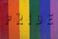 PRIDE concept. Background with embossed lettering on a wall with texture and colors of the rainbow flag Royalty Free Stock Photo