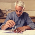 He prides himself on his accuracy. a draftsman using a triangle and compass to draw up building plans.