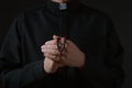 Priest with beads praying on dark background, closeup Royalty Free Stock Photo