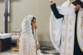 Priest blessing with holy water stylish bride in kerchief at altar during holy matrimony in church. Wedding ceremony in cathedral Royalty Free Stock Photo