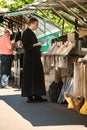 Priest at book stall along river Seine.