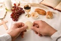 Priest breaking sacred bread to distribute it to the communicants