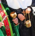 priest with cassock and aspergillum while performing the blessing also with holy water and incense