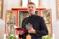 Priest in church with bible in front of altar