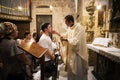 Priest of the Church of Holy Sepulchre gives holy communion to faithful man with other believers waiting for their turn. Jerusalem