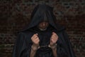 A priest handcuffed against the background of a stone wall. Concept: old criminal, criminal responsibility, Royalty Free Stock Photo