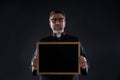 Priest holding empty blackboard copy space Royalty Free Stock Photo