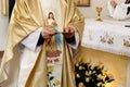 Priest holding golden plate for communion at wedding ceremony at church