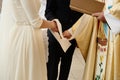 Priest holding hands of stylish bride and elegant groom at catholic wedding ceremony at church Royalty Free Stock Photo