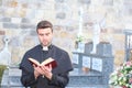 Priest with holy bible in a cemetery Royalty Free Stock Photo