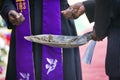 priest and mourner holding a spade with ground to bless the grave