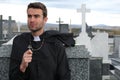 Priest performing an exorcism in a windy cemetery