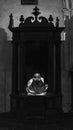 Priest praying inside a booth in a Cathedral black and white