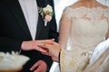 Priest puts wedding ring at grooms hand at church.