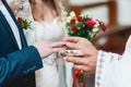 Exchanging wedding rings. priest putting on golden wedding rings on fingers bride and groom in church at wedding matrimony