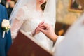 Priest is putting the ring on bride's finger during wedding ceremony