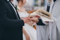 Priest is putting ring on groom`s finger during orthodox wedding ceremony