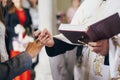 Priest putting on stylish wedding ring with feather on groom finger in during holy matrimony in church. Wedding ceremony in