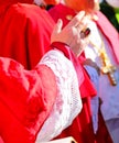 priest with red cassock during the blessing of the faithful at the end of the solemn mass