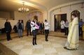 Priest standing in rural church in front of women holding abies on hands and praying. Ukrainian traditional ceremony of