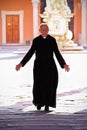 Priest walking on the churchyard in Pisa.