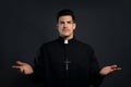 Priest wearing cassock with clerical collar on black