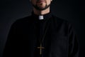 Priest wearing cassock with clerical collar on dark background, closeup