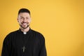 Priest wearing cassock with clerical collar on yellow background, space for text Royalty Free Stock Photo
