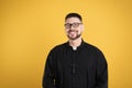 Priest wearing cassock with clerical collar on yellow background Royalty Free Stock Photo