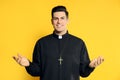 Priest wearing cassock with clerical collar on yellow background