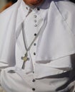 priest with white cassock and small silver cross