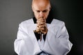 Priest in white surplice and black shirt praying with wooden rosary Royalty Free Stock Photo