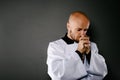 Priest in white surplice and black shirt praying with wooden rosary Royalty Free Stock Photo