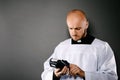 Priest in white surplice and black shirt with white collar holding credit card terminal.