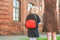 Primary school student and parent go hand in hand. A woman and a young girl with a backpack behind her back. The beginning of the. Royalty Free Stock Photo