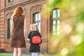 Primary school student and parent go hand in hand. A woman and a young girl with a backpack behind her back. The beginning of the Royalty Free Stock Photo