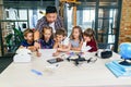 School teacher at desk works with five young pupils using digital tablet computer in technology class. Development Royalty Free Stock Photo