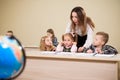 Primary school teacher helping a girl writing at her desk. Royalty Free Stock Photo