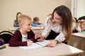 Primary school teacher helping a girl writing at her desk. Royalty Free Stock Photo