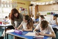 Primary school teacher helps a pupil at desk with classwork Royalty Free Stock Photo