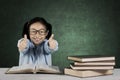 Primary student with ok gesture and books on table