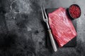 Prime choice flank steak, raw beef meat on marble board with herbs. Black background. Top view. Copy space