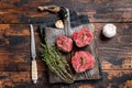 Prime raw Fillet mignon steaks on a wooden board with thyme and garlic. Dark wooden background. Top view