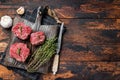 Prime raw Fillet mignon steaks on a wooden board with thyme and garlic. Dark wooden background. Top view. Copy space